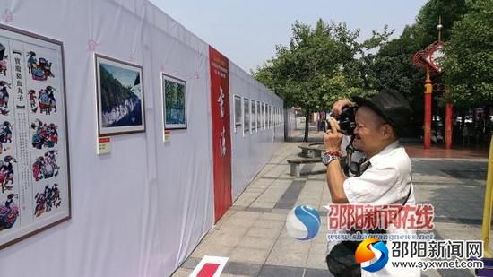 王雄杰老人正在书法美术摄影展上拍摄自己心仪的作品。 贺旭艳 摄