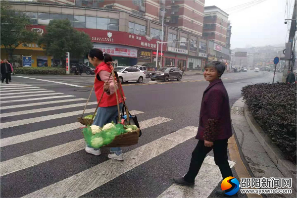 志愿者为卖菜的大妈挑起了“重担”